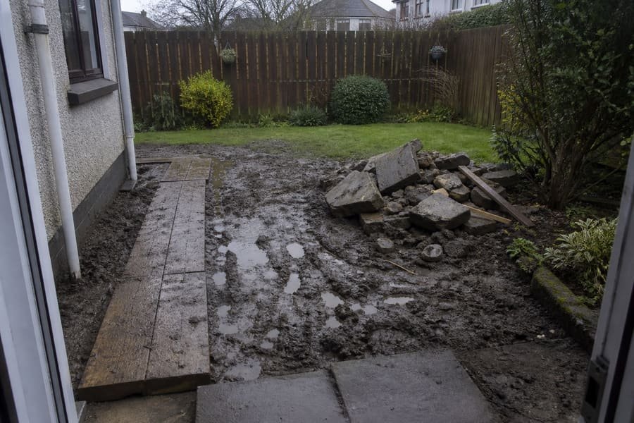 Muddy unfinished rear garden with standing water and scattered rubble.