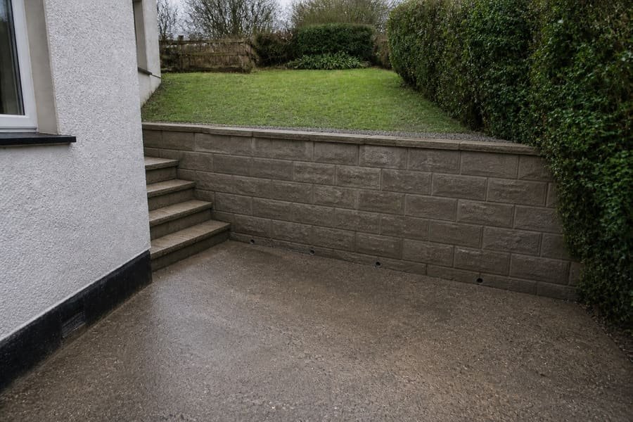 The same slope held by a faced block retaining wall with steps up to the lawn.