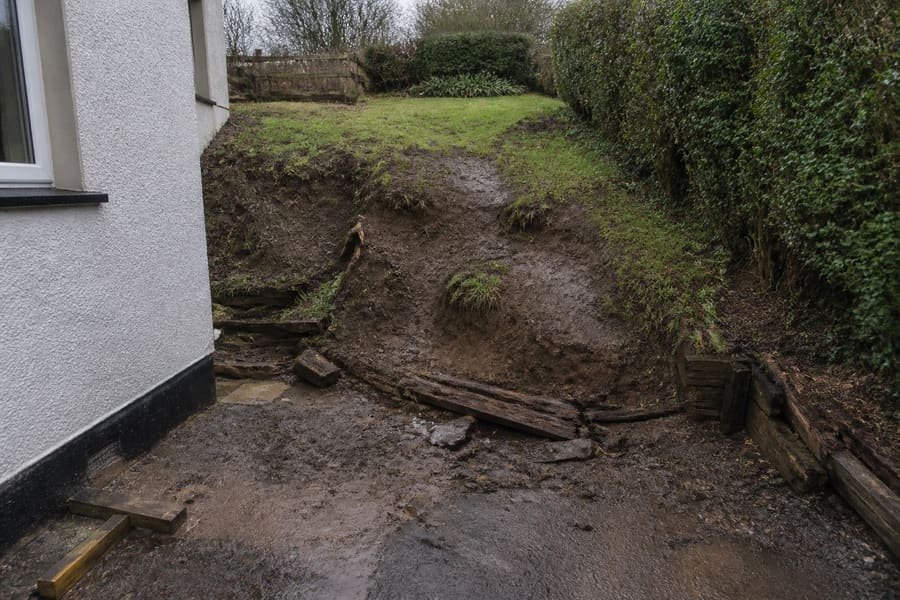 Eroding sloped garden bank with exposed roots and washed silt.